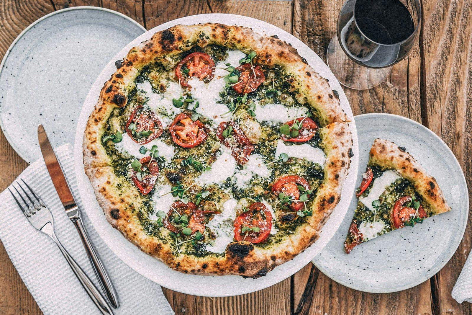 A very vibrant margherita pizza paired with a glass of red wine