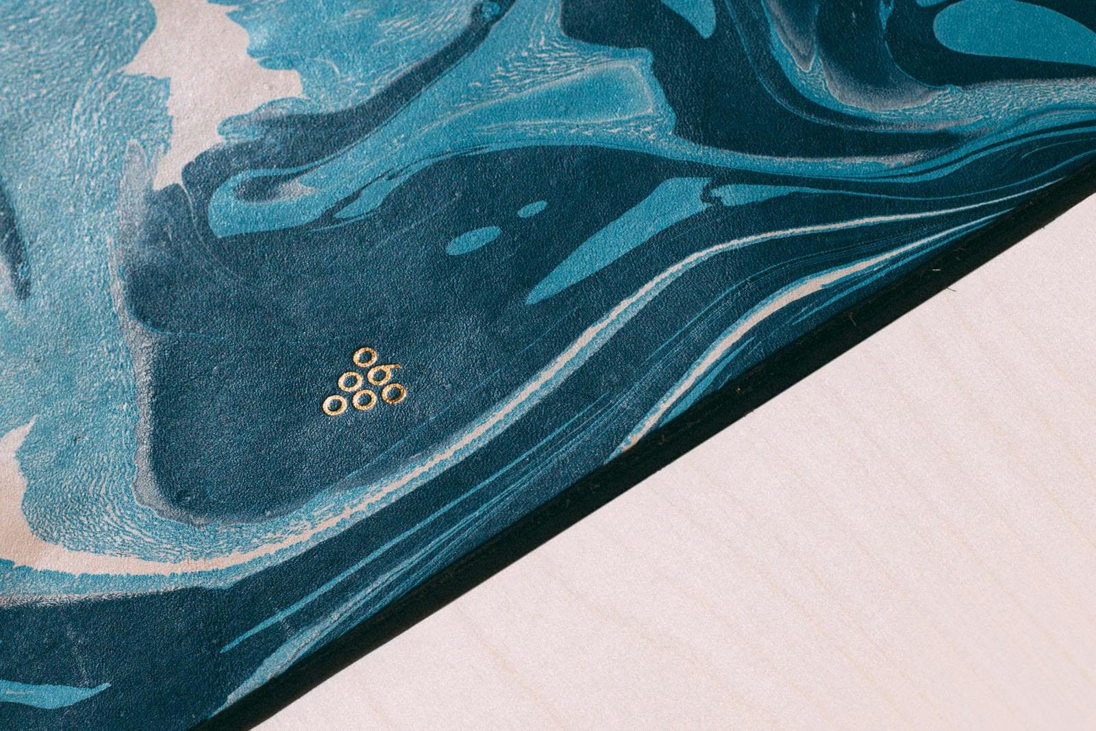 A close up of the Sixty Vines logo in gold on a blue marble background