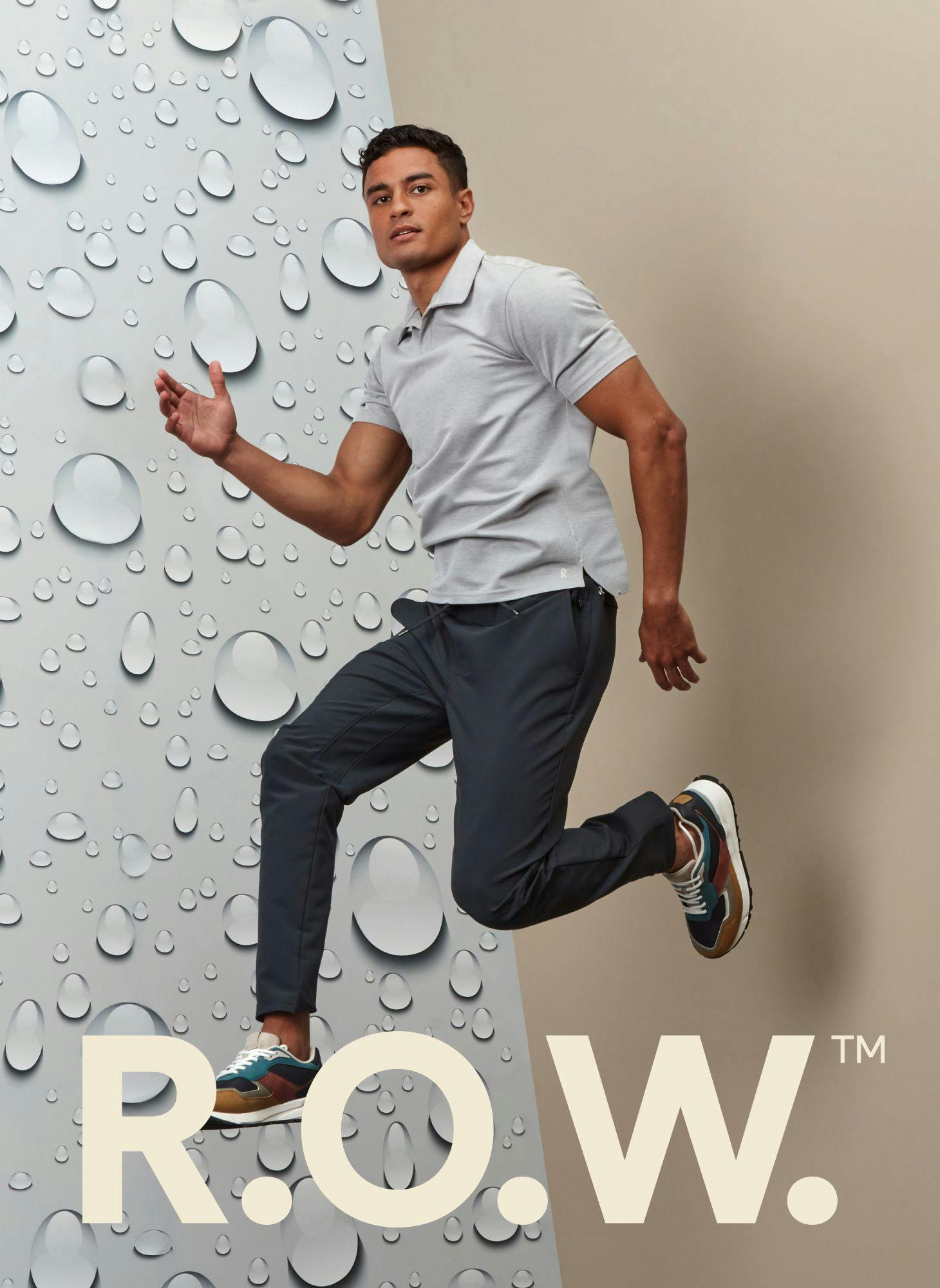 Man posing in R.O.W. activewear in front of a beige and water droplet background