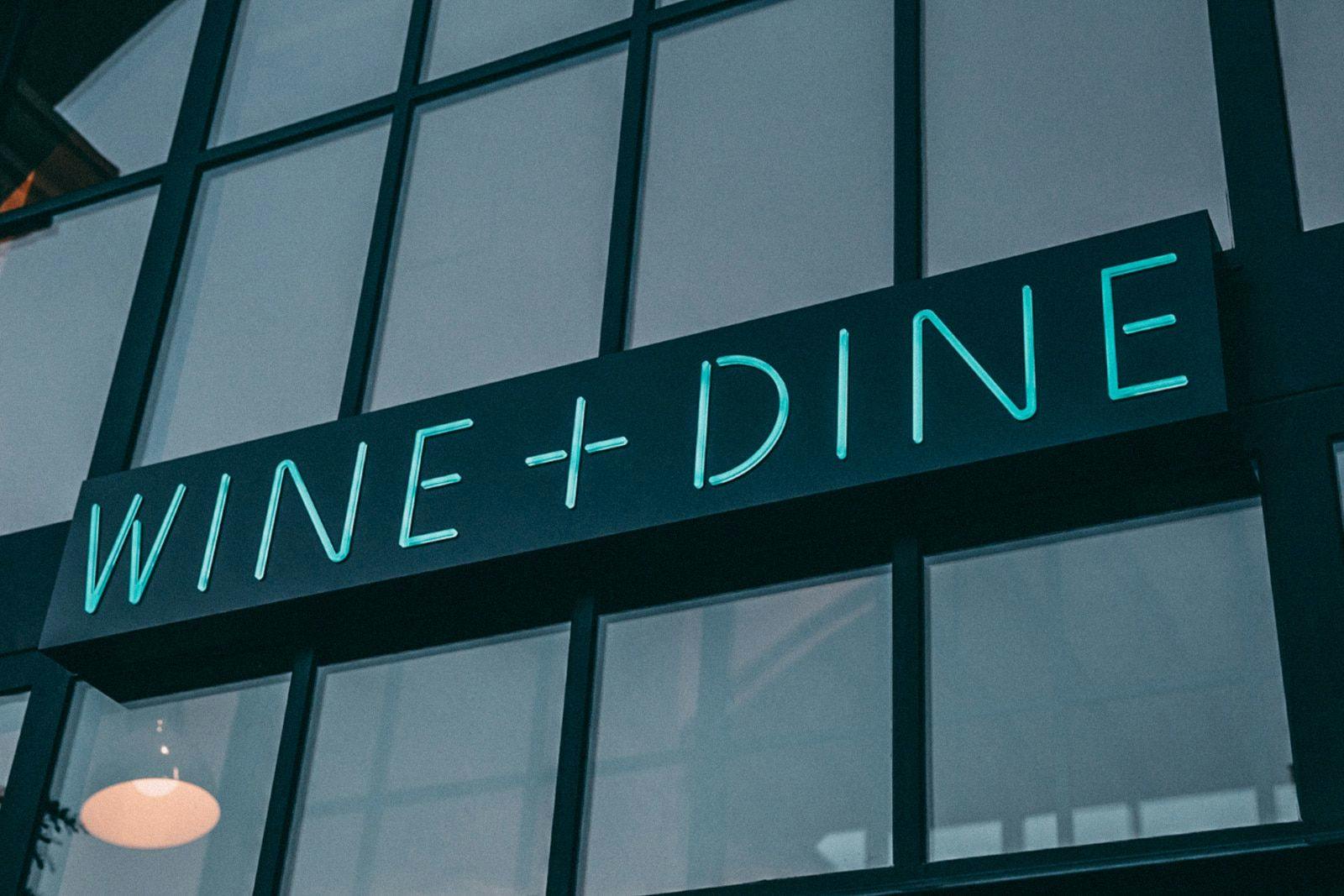 Wine + Dine neon sign on the exterior of a Sixty Vines restaurant